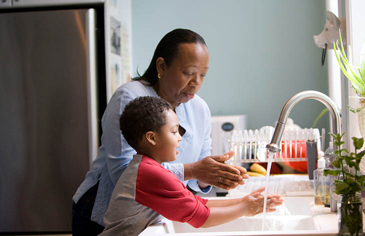 A child washing their hands with their mother.
